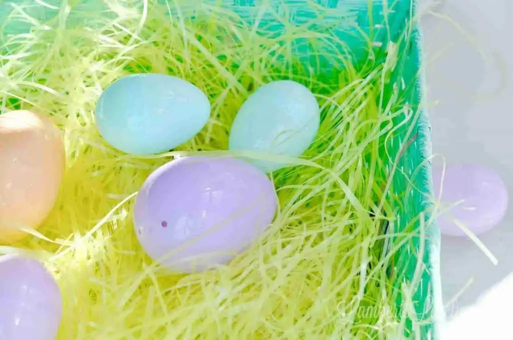 plastic easter eggs in an easter basket with yellow plastic grass.