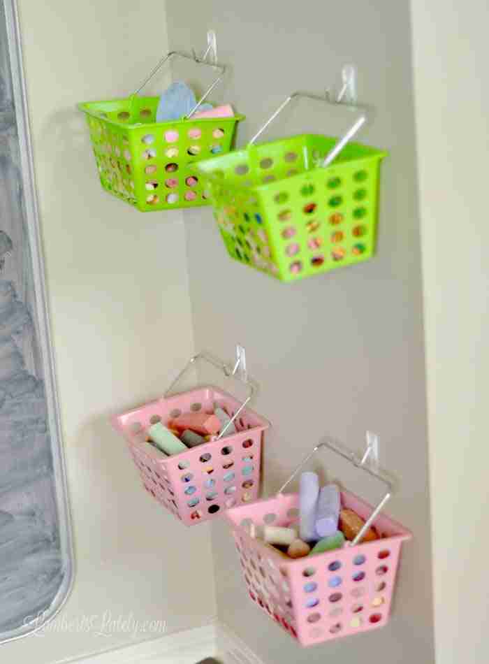 green and pink plastic baskets holding chalk, fastened to a wall.