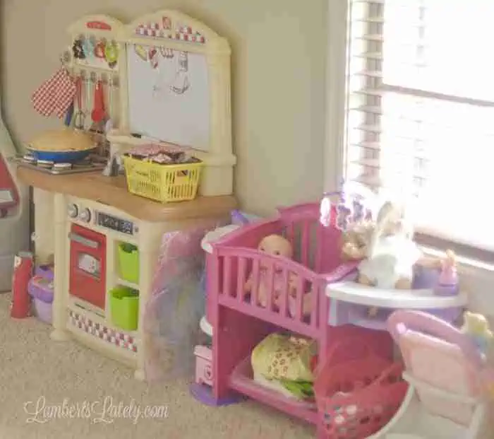 toys (kitchen, crib, stroller) in a playroom.