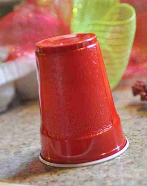 solo cup in front of red and green deco mesh ribbon, ornament holder.