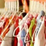 Clothes hanging on a rack at a consignment sale with organization hacks text.