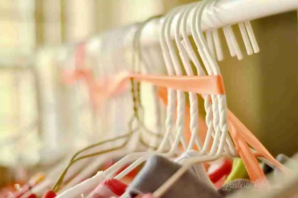 white wire hangers tied together with plastic, hanging on a rack.