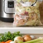 Frozen veggie scraps in a bag for pressure cooker veggie broth preparation.