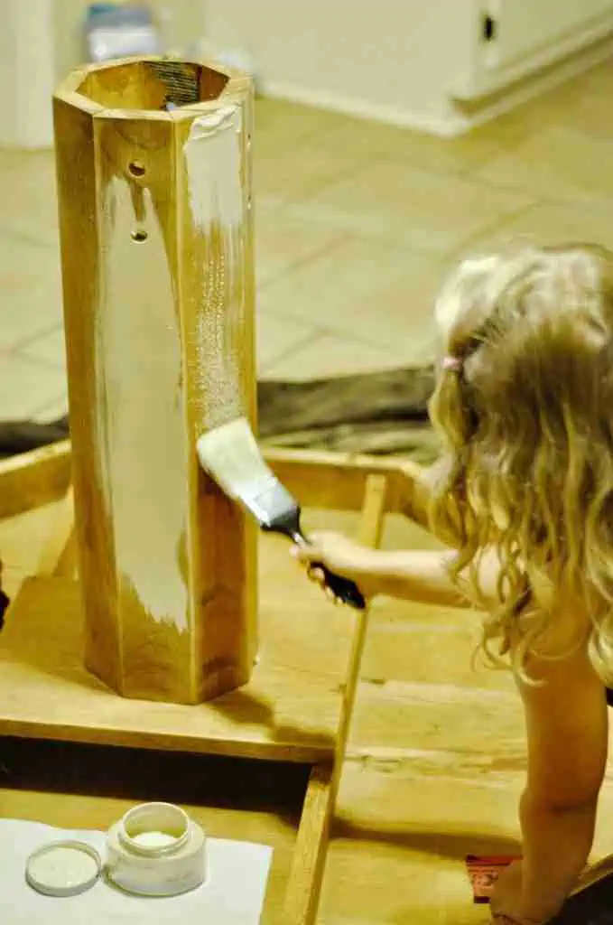 child painting the base of a table.
