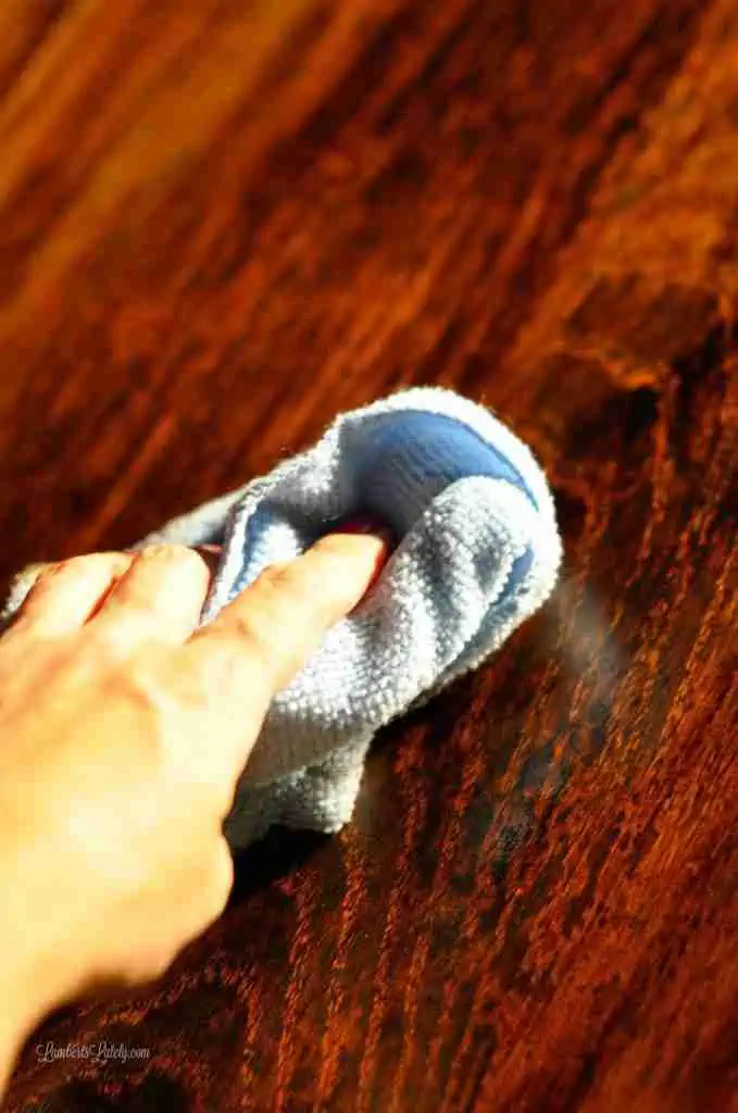 wiping wood stain off of table with a rag.