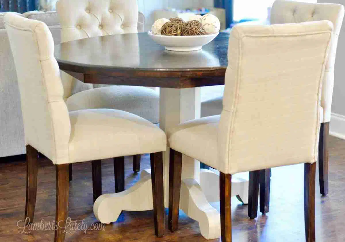 wood stained and white table with white upholstered chairs around.