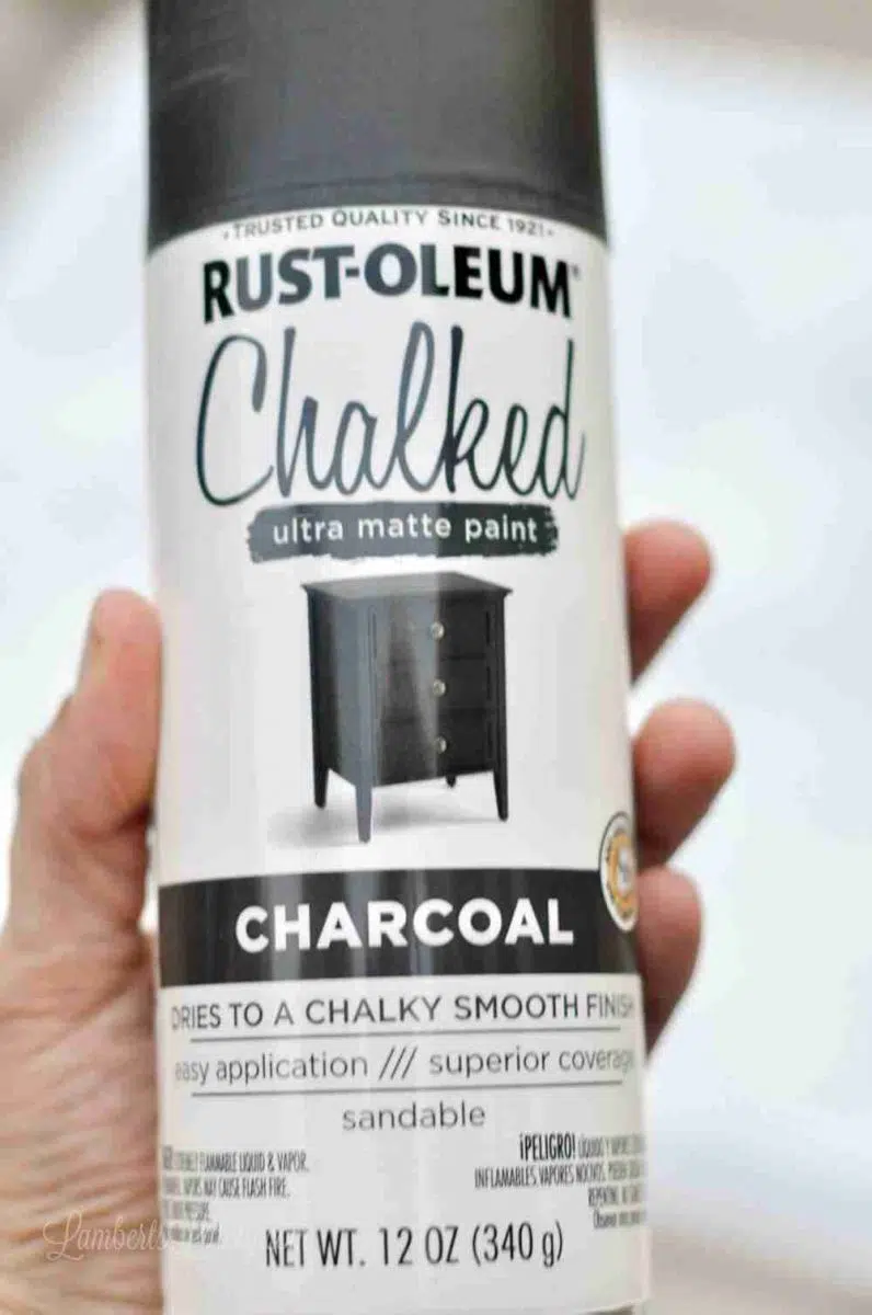 holding a bottle of rust-oleum chalked charcoal spray paint.