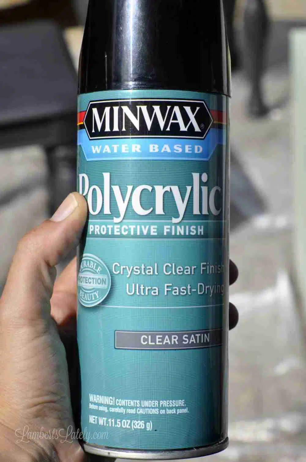holding a spray paint can of minwax polycrylic.