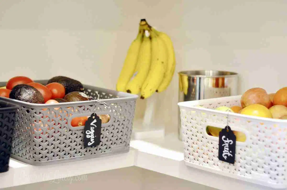 plastic bins on a shelf, holding food. banana hanger.