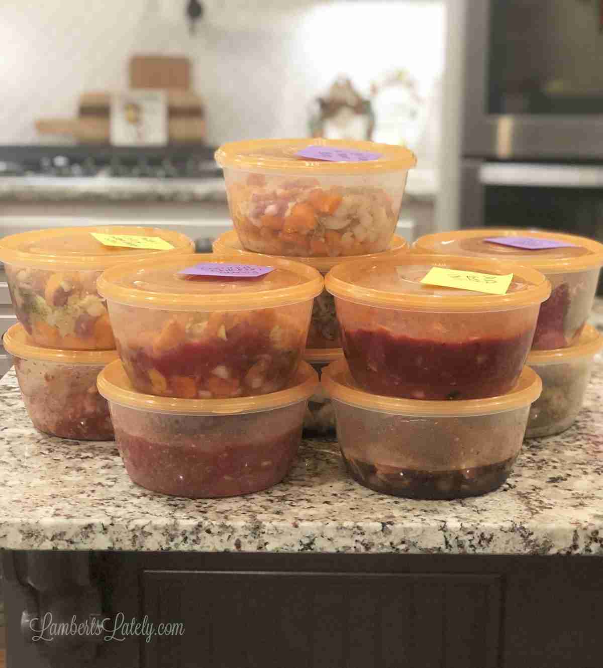 freezer meals in containers stacked on a counter.