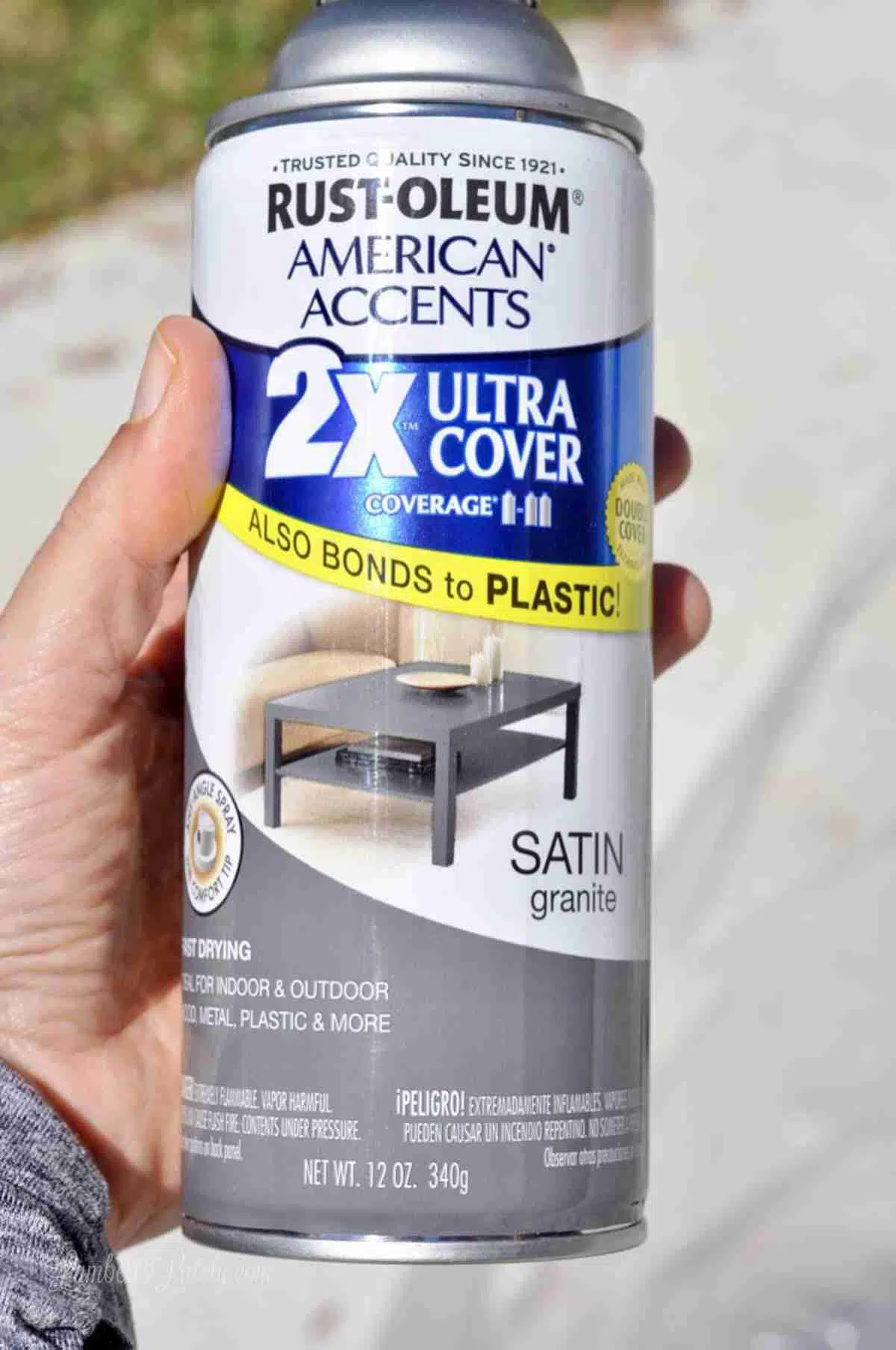 holding a can of rust-oleom gray spray paint.