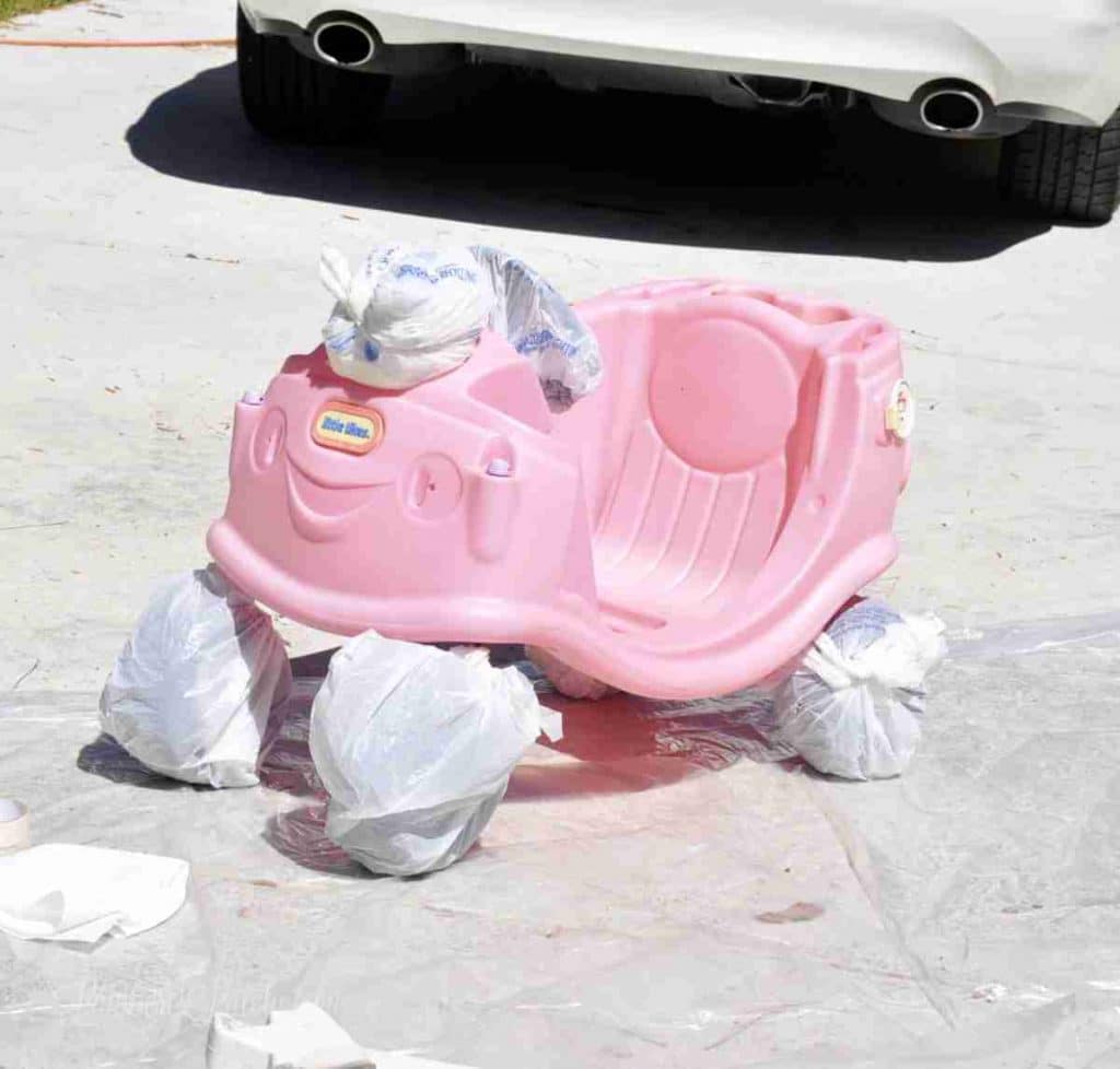 bottom base of cozy coupe with wheels, eyes, steering wheel wrapped in plastic shopping bags.