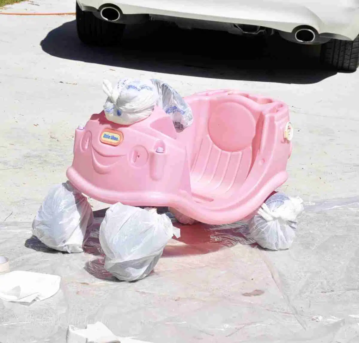 bottom base of cozy coupe with wheels, eyes, steering wheel wrapped in plastic shopping bags.