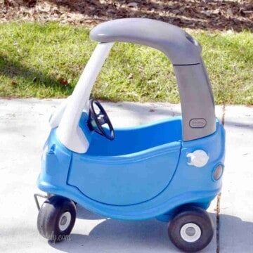 blue and gray cozy coupe toy car in a driveway.