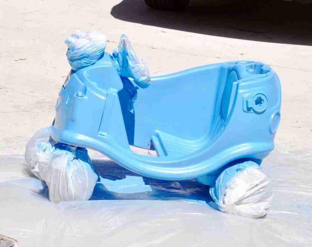 cozy coupe base, wheels and steering wheel wrapped in plastic shopping bags, after painting blue.