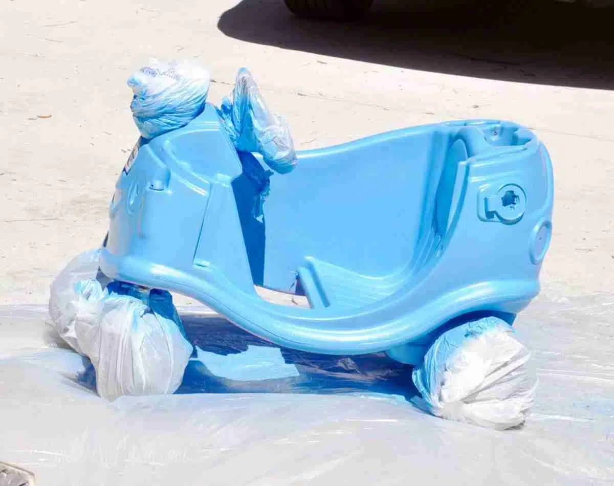 cozy coupe base, wheels and steering wheel wrapped in plastic shopping bags, after painting blue.
