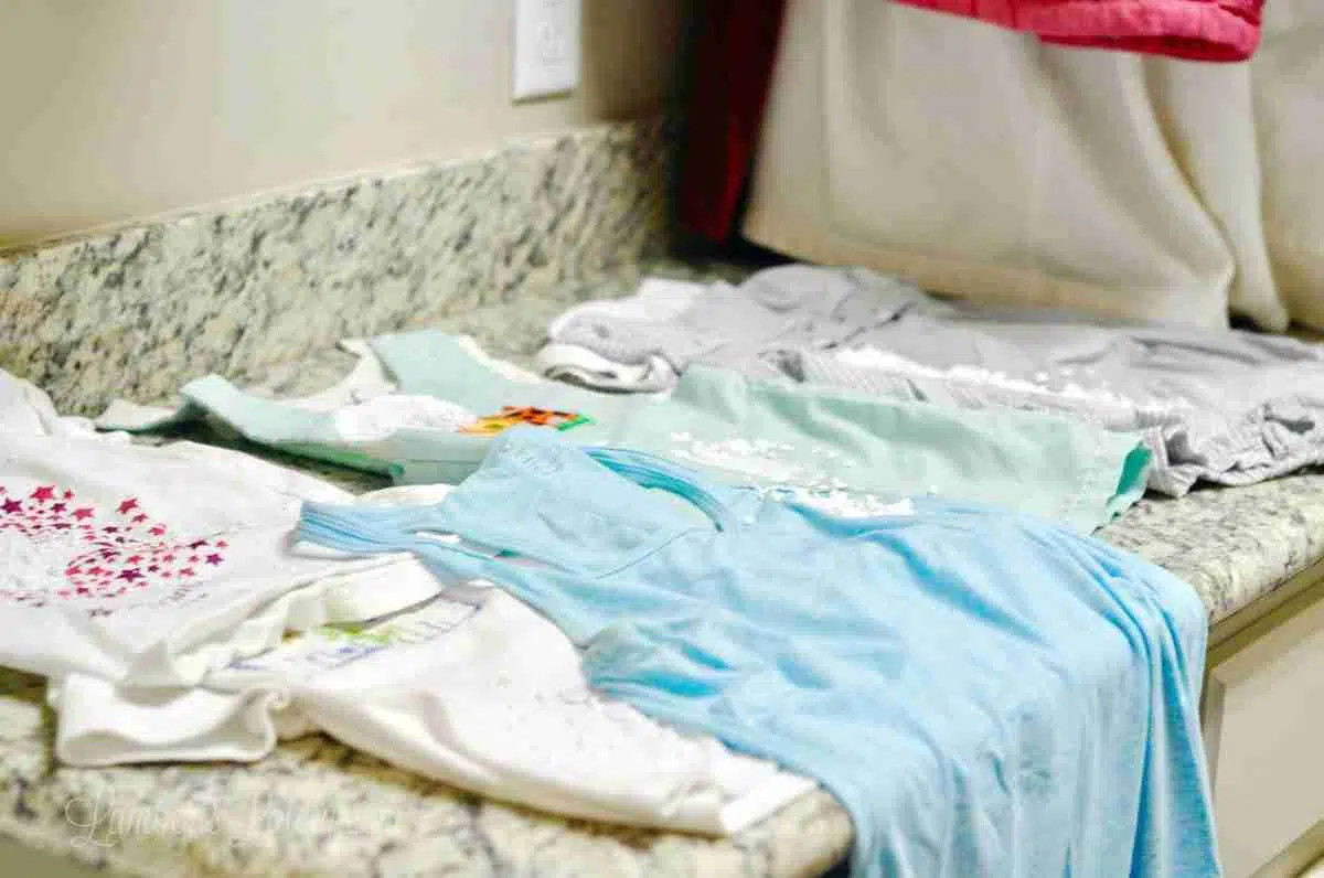 clothes covered in oxiclean paste, laid out on a laundry room counter.