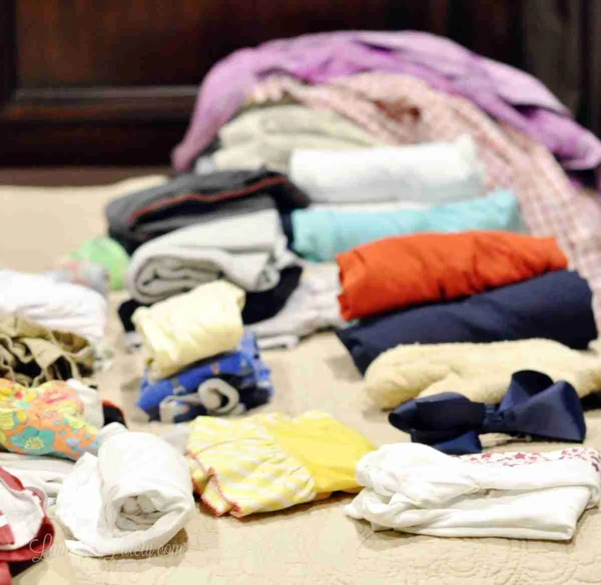 clothes folded and rolled on a bed.