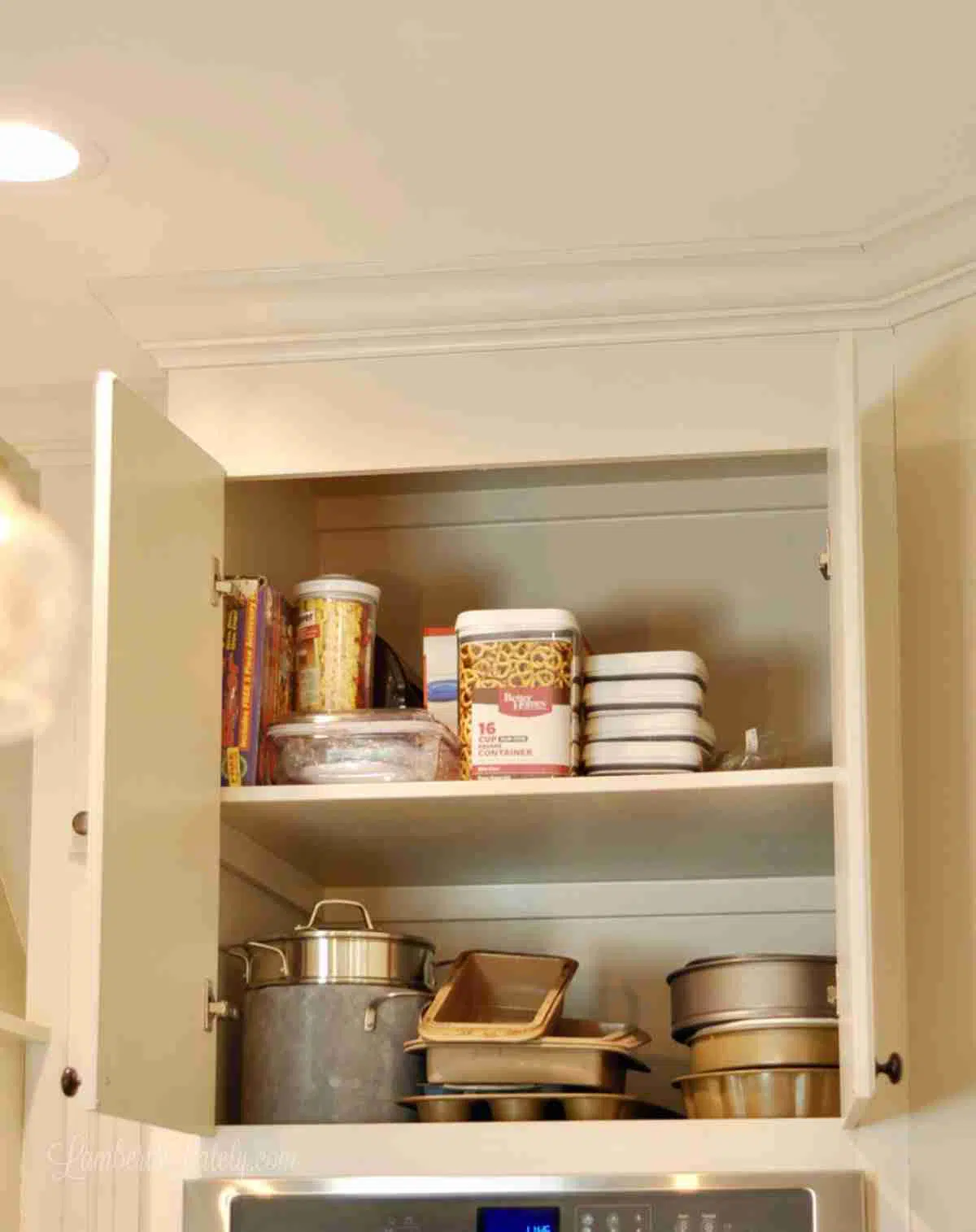 kitchen cabinet holding pots, pans, containers.