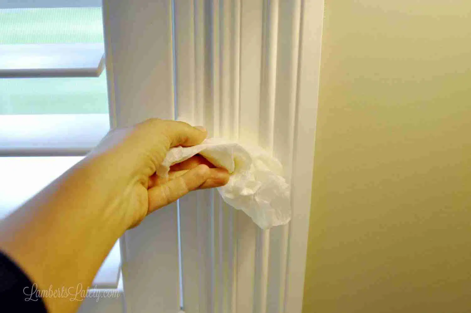 using wet paper towel to smooth caulk in window gap.