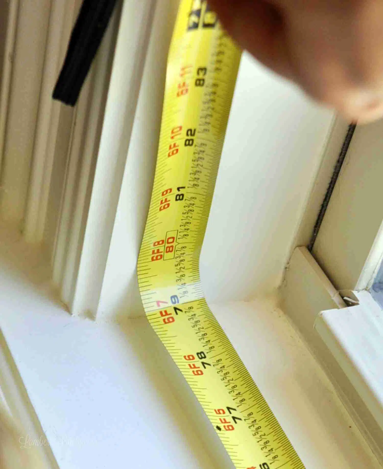 measuring the height of a window with a metal measuring tape.