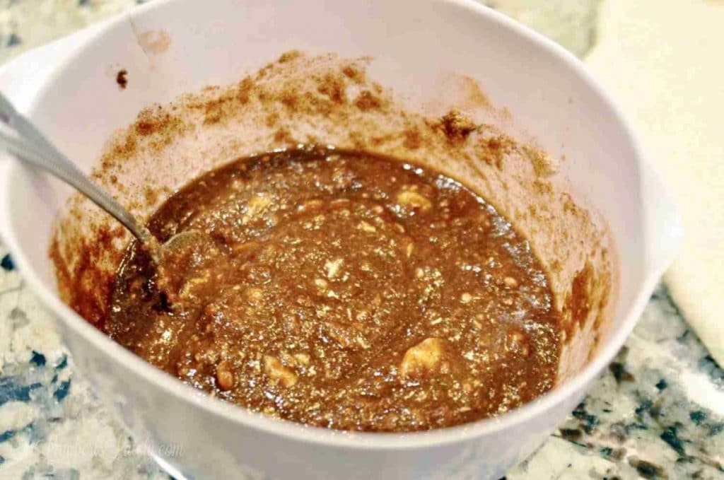 Close-up of cinnamon filling mixture in a white bowl with a spoon.