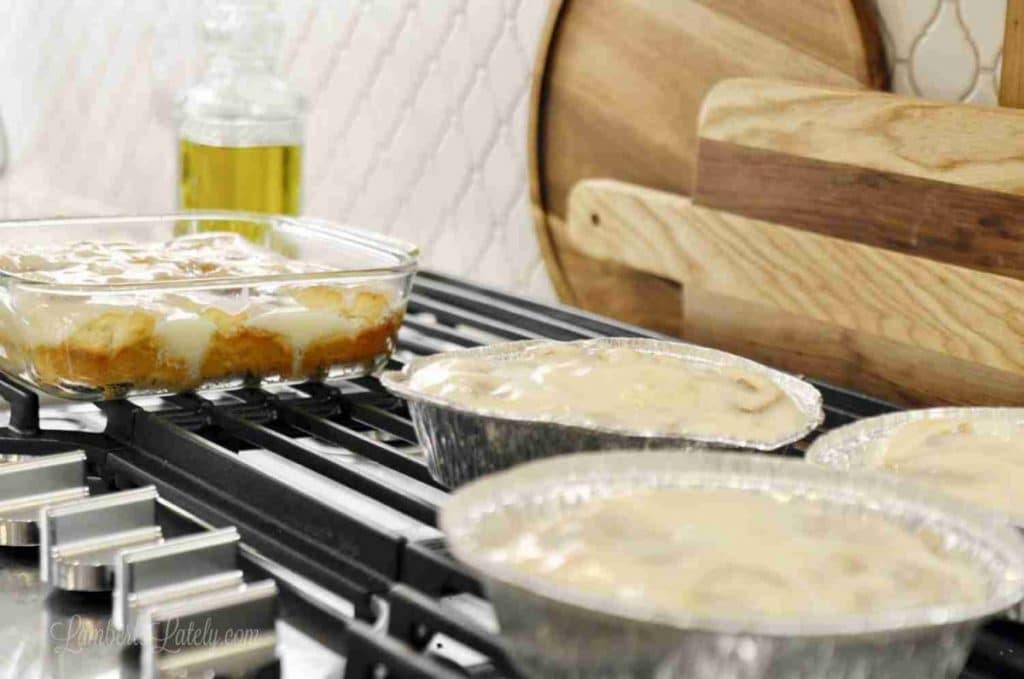Unbaked cinnamon rolls with cream cheese frosting in glass bowls on stovetop.