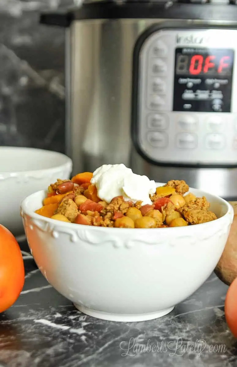 bowl of turkey chili topped with sour cream in front of an instant pot.