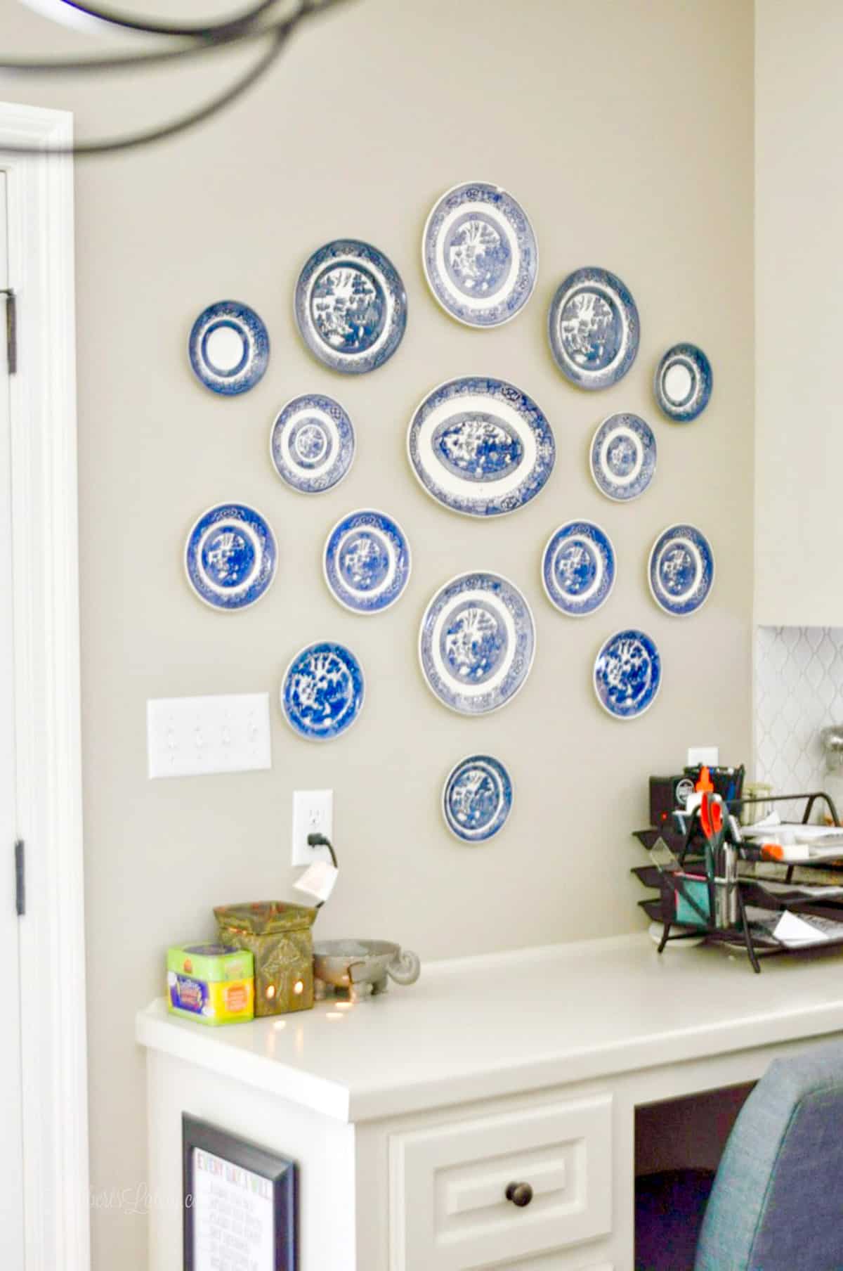collection of blue and white plates and platters hanging above a desk.