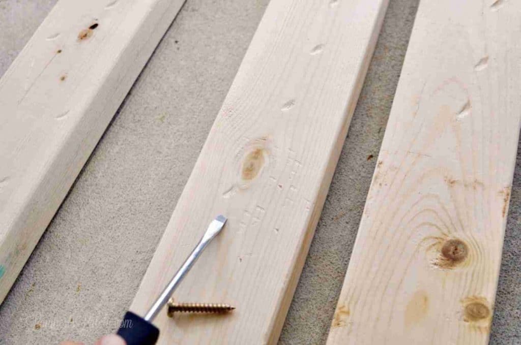 distressing 2x4 wood with a screwdriver and screw.