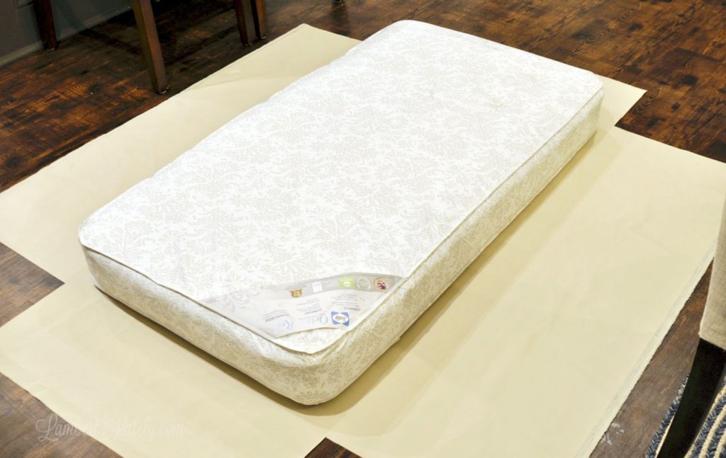 crib mattress laying on top of the start of a cover