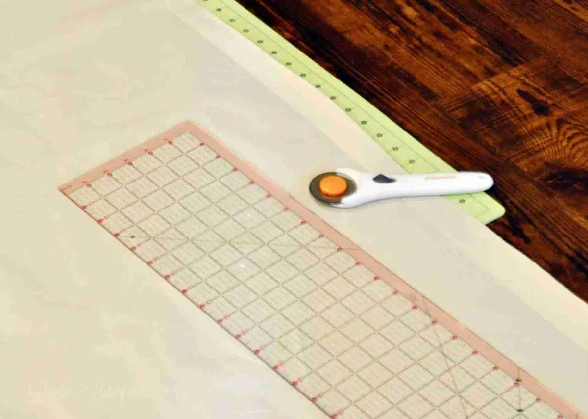 rotary cutter, quilting ruler on top of piece of fabric.
