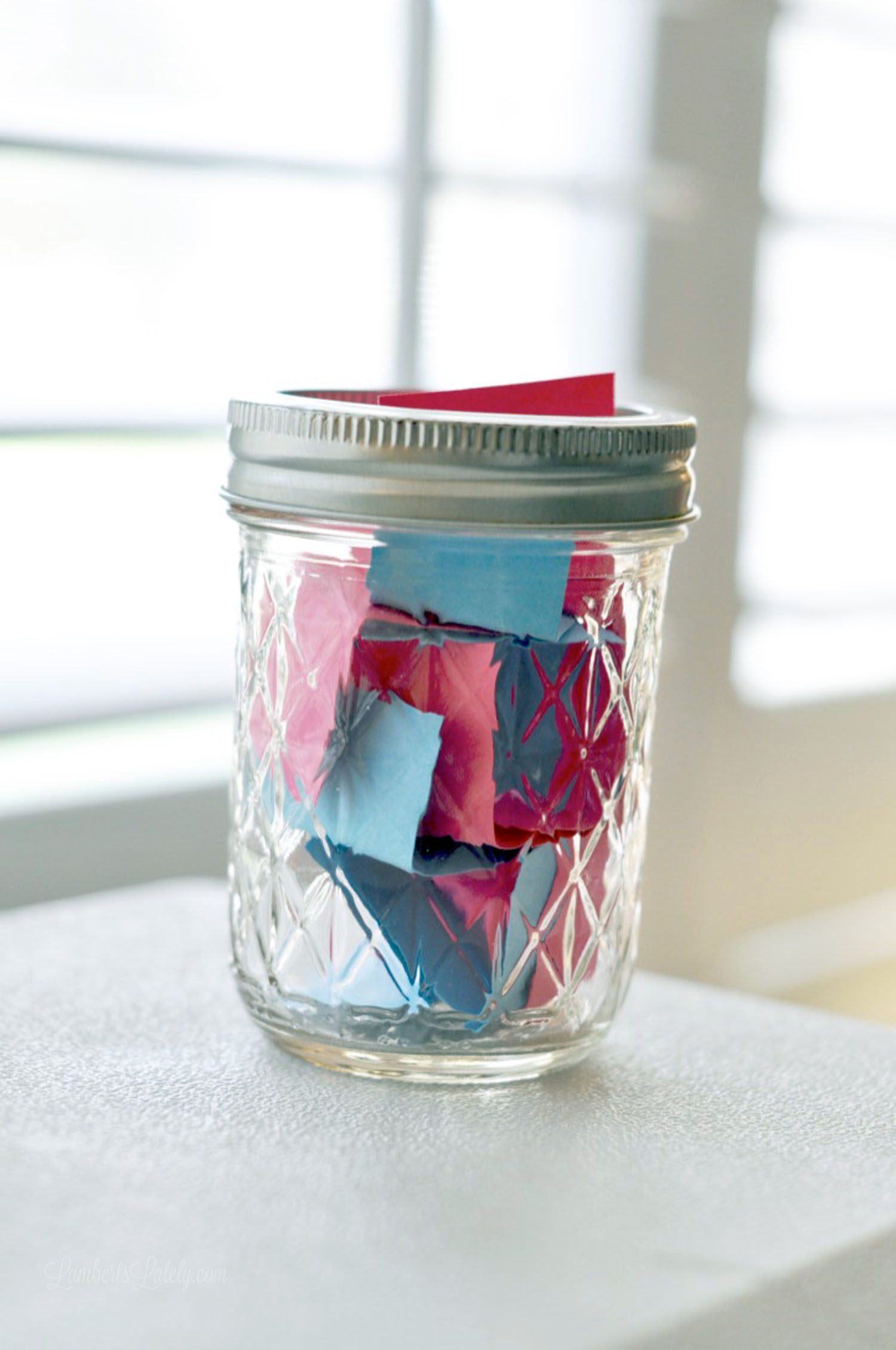 jar with blue and pink paper strips inside.
