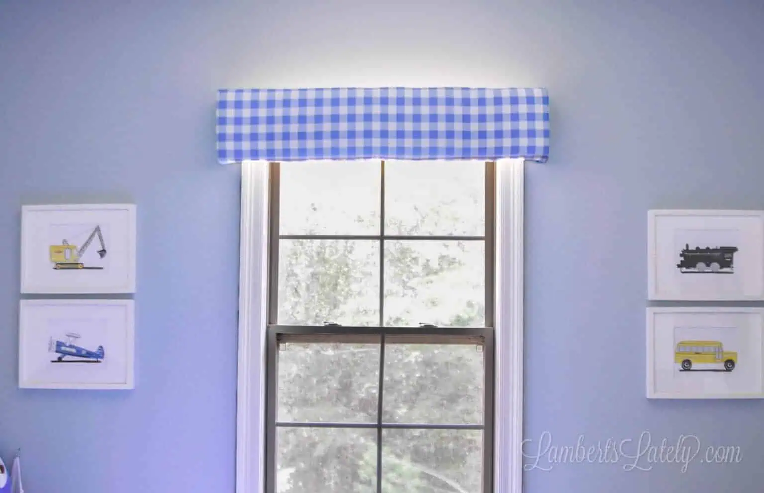 cornice board hung above a window, with framed pictures on each side of window.