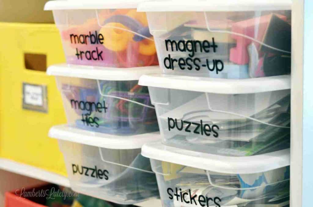 labeled plastic bins on a playroom shelf.