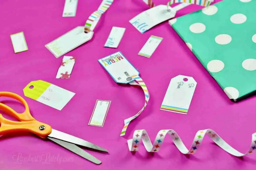 a wrapped gift and free printable christmas gift tags spread out with ribbon, scissors.