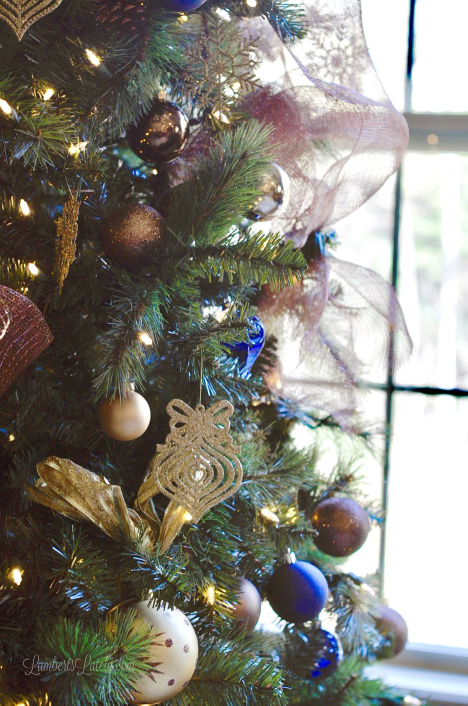 close up of ribbon, blue, gold, and brown ornaments in a christmas tree.