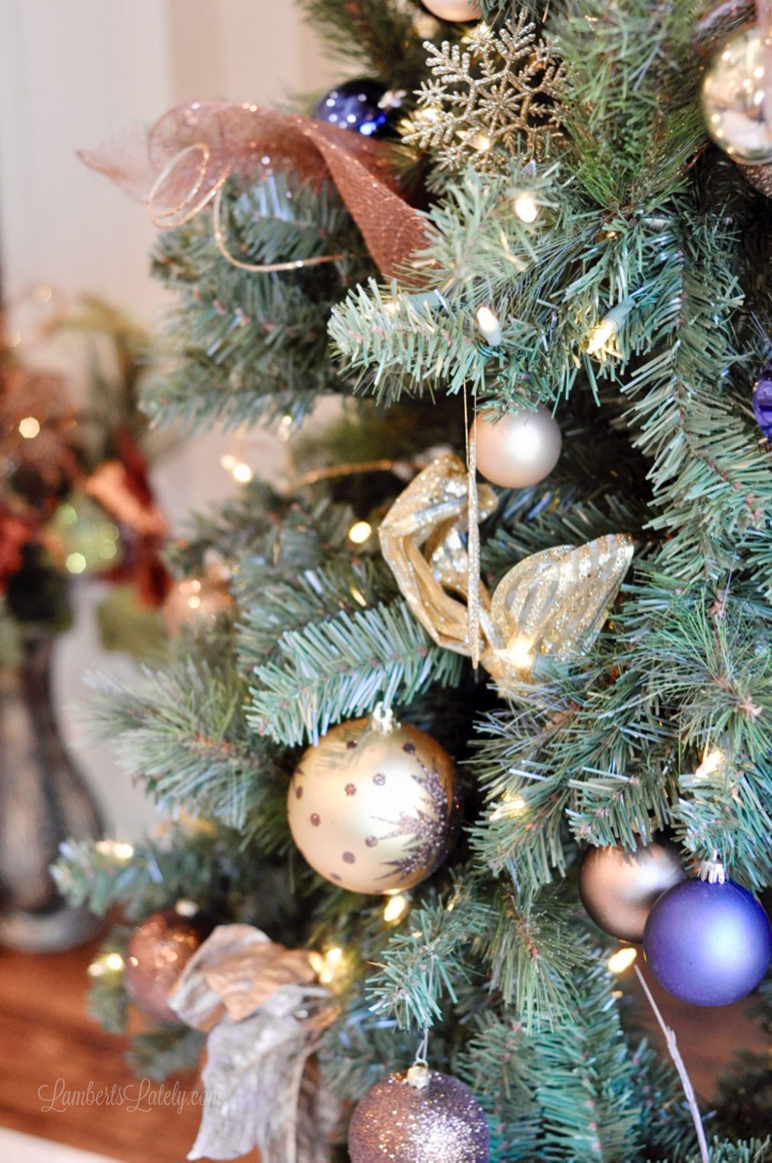 close up of ribbon and blue and brown ornaments in a christmas tree.
