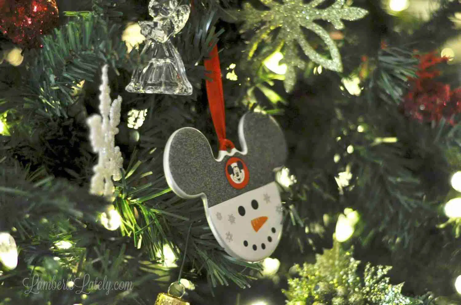 mickey mouse snowman ornament on a tree.
