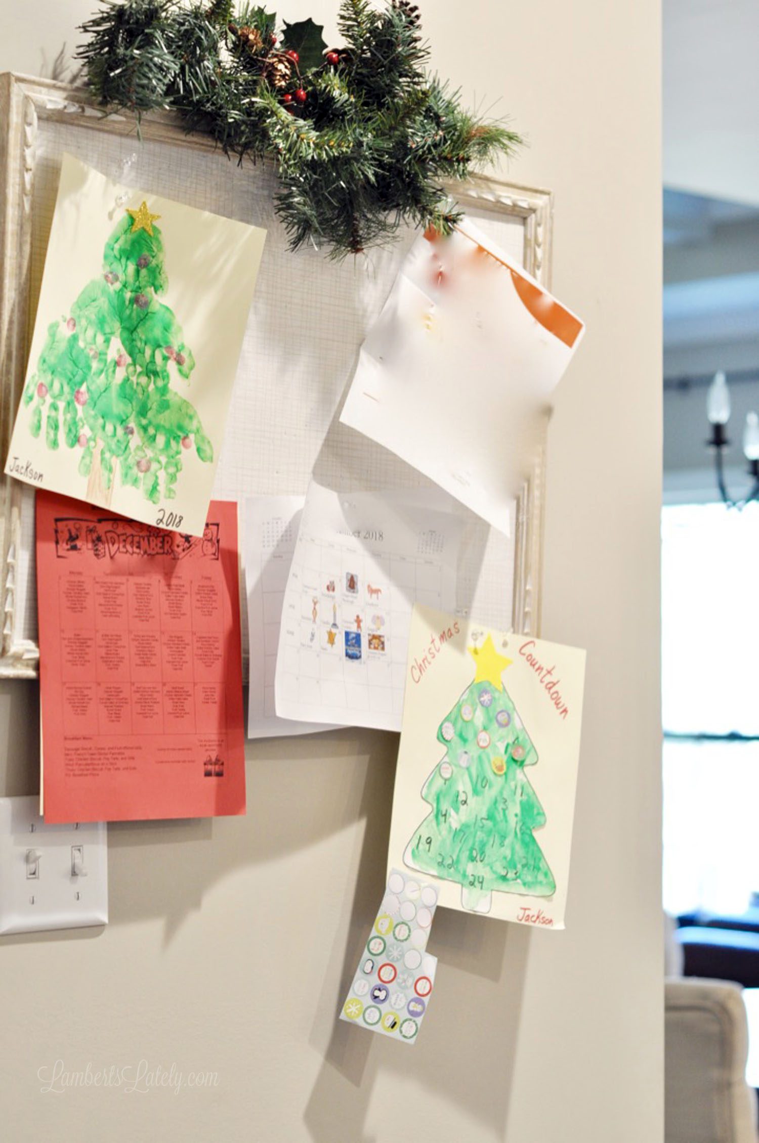 children\'s christmas drawings hanging on a peg board.