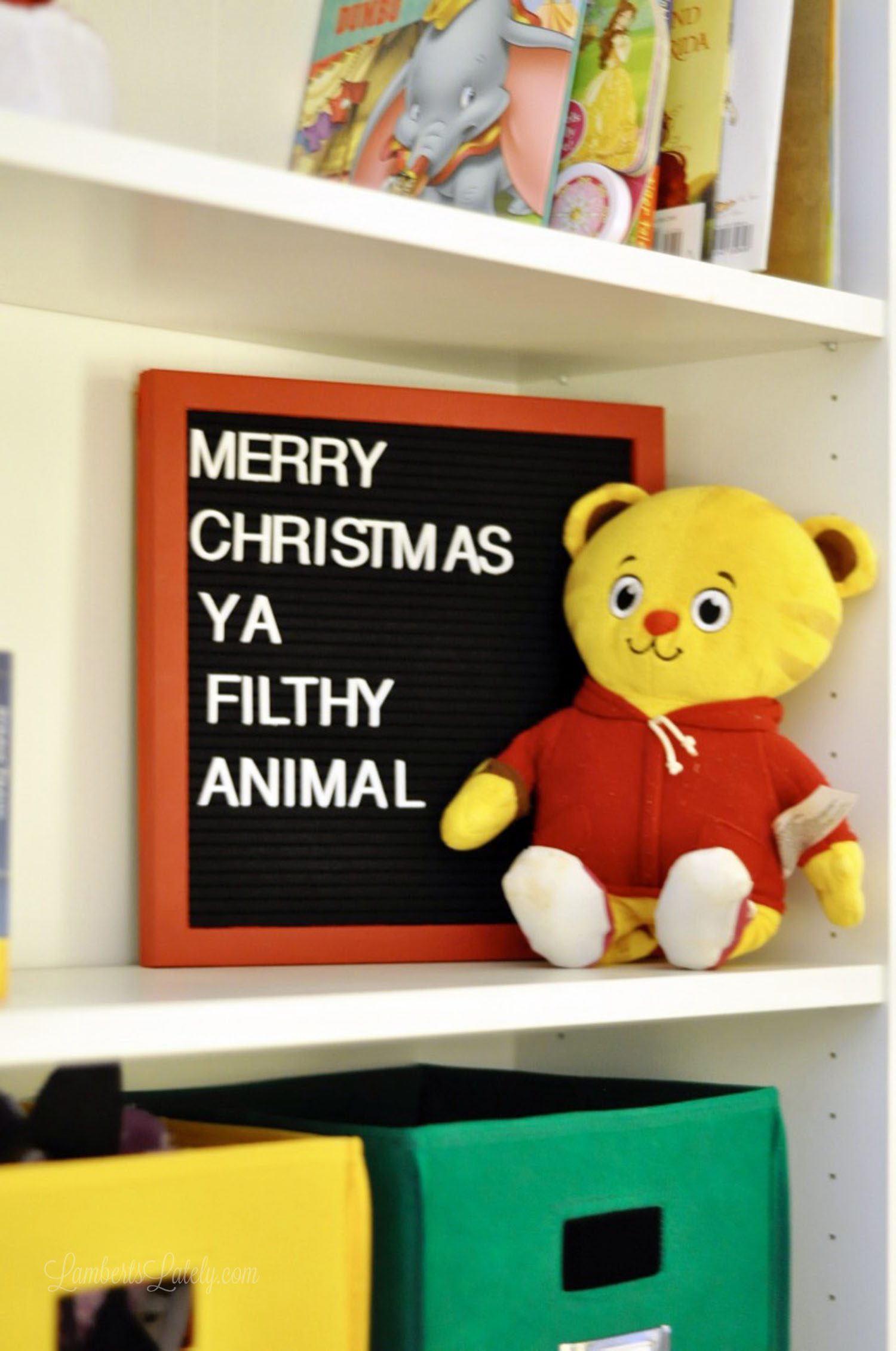 letter sign with merry christmas ya filthy animal, stuffed animal in front.