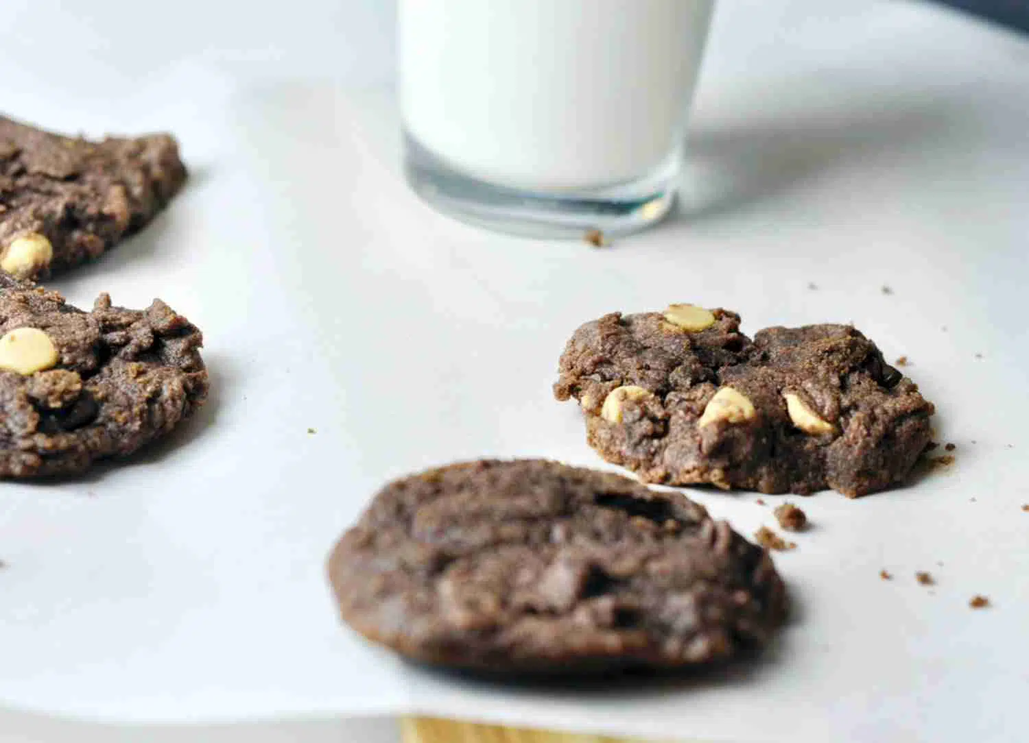 chocolate chip pudding cookies on a piece of parchment paper, with glass of milk.