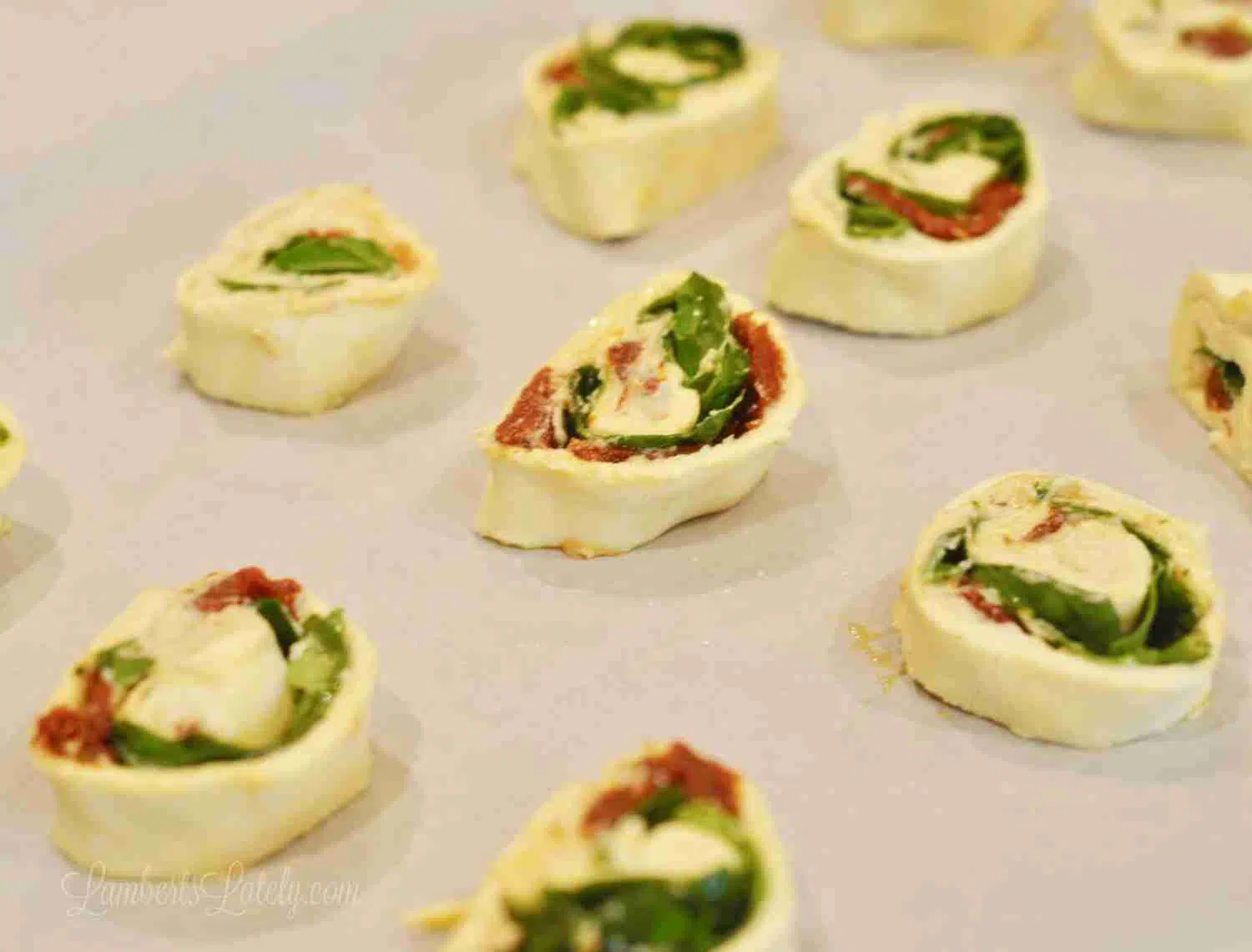 hummus pinwheels, before baking, on a baking sheet lined with parchment paper.