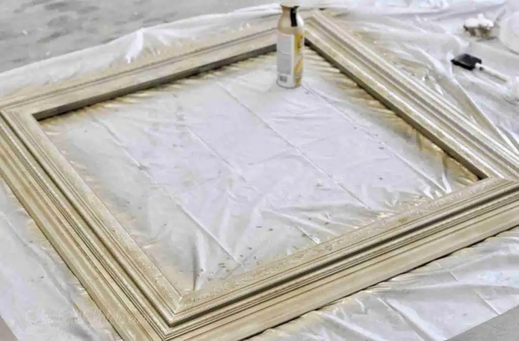 gold frame on a tarp after painting with spray paint.