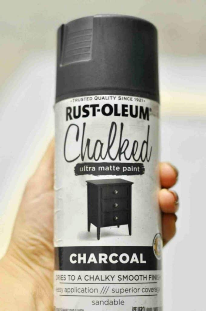 holding a bottle of chalk black spray paint.