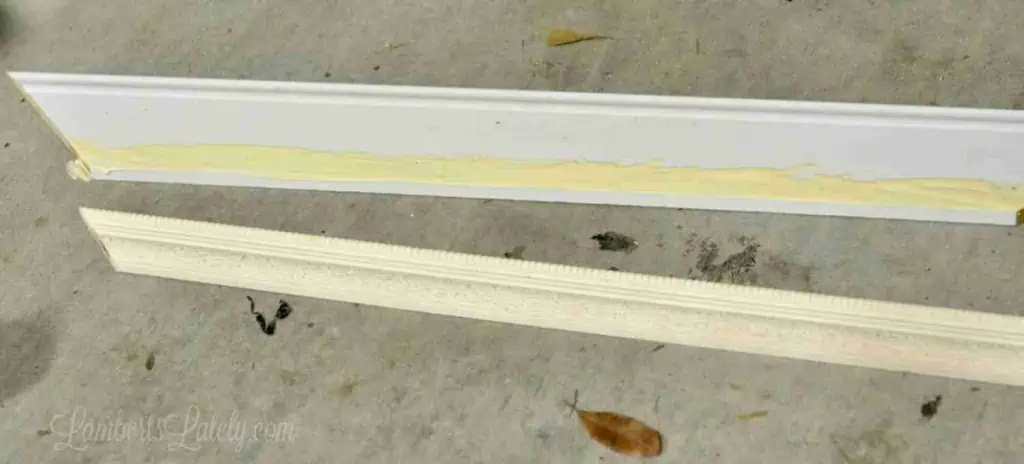 one piece of molding with glue, one laying next to it on a garage floor.