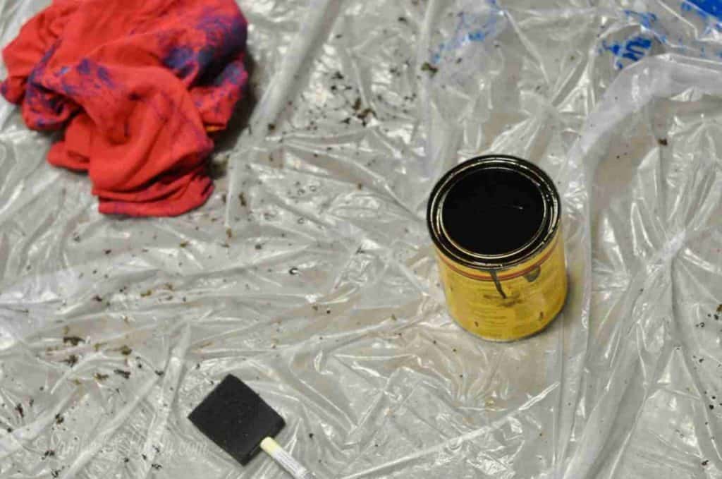 wood stain, brush, tshirt on a dropcloth.