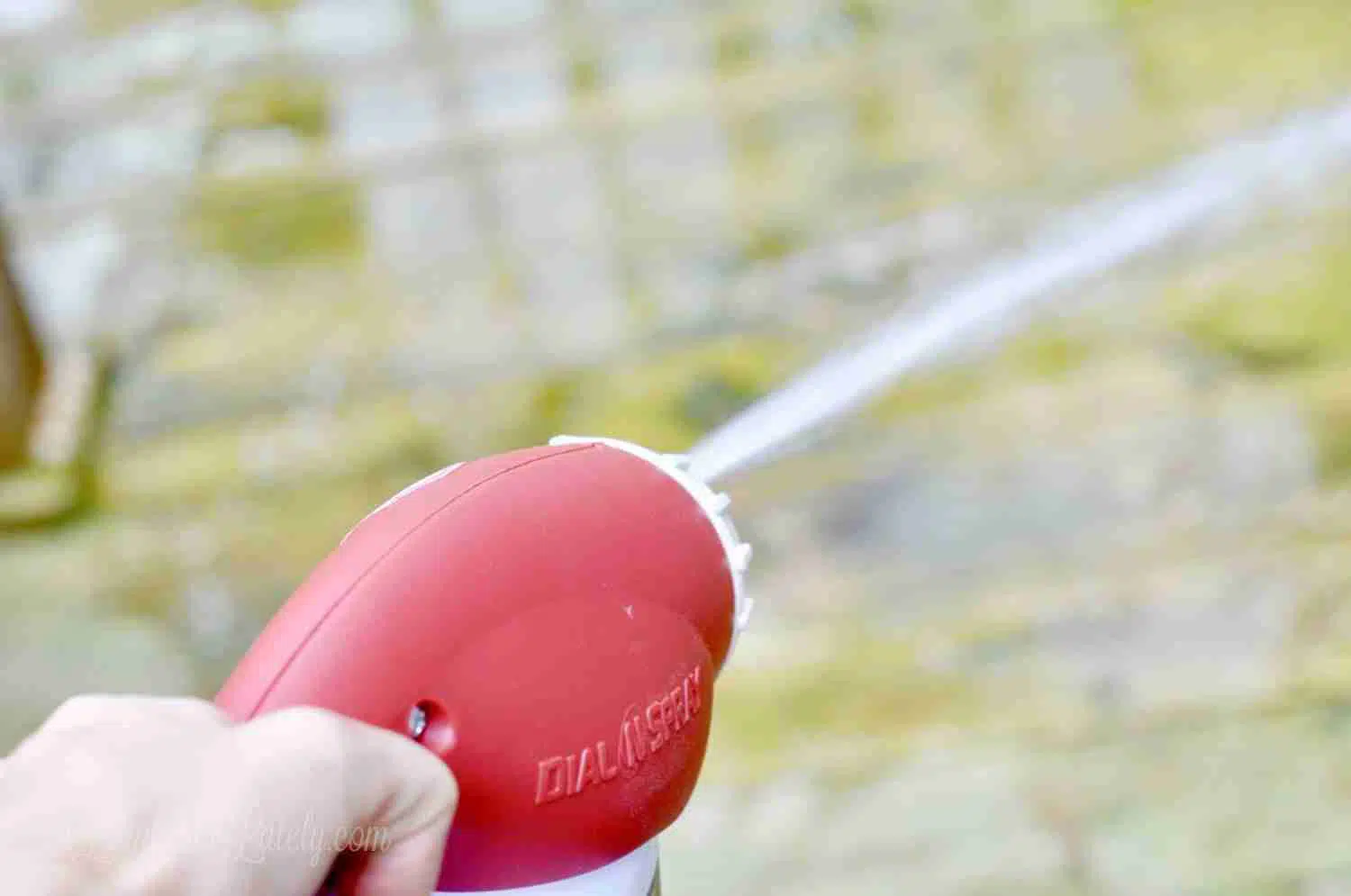 holding a red sprayer nozzle.