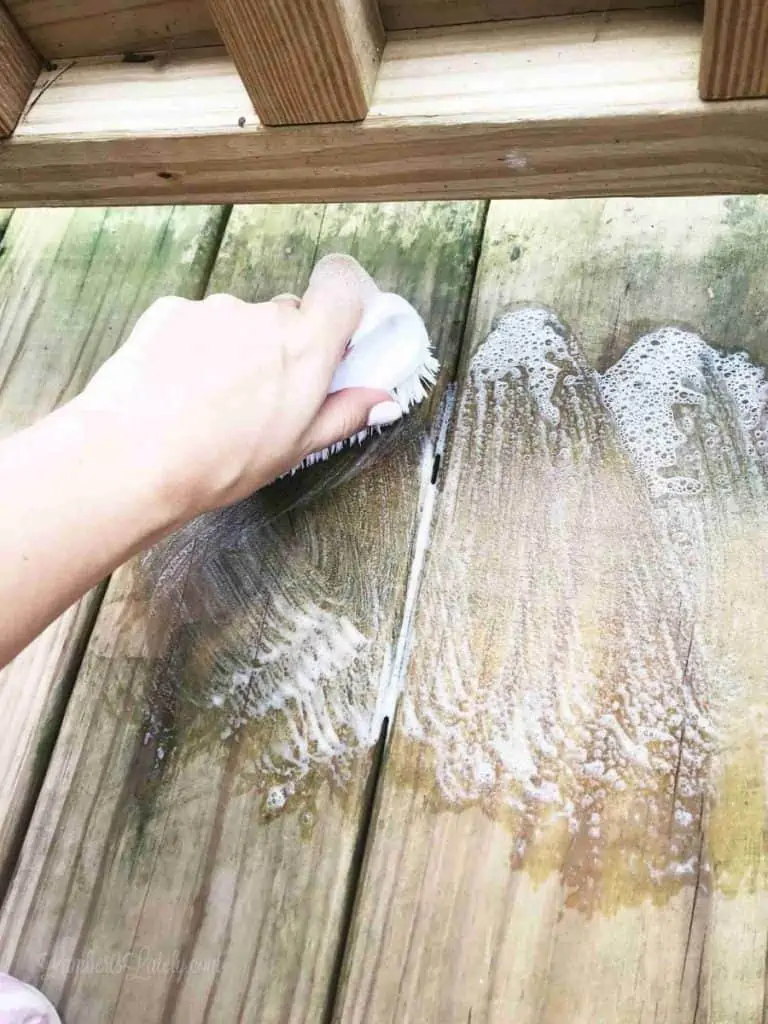 scrubbing green stains under railing on a deck.