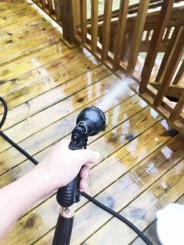 spraying a wood deck with a hose.